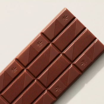"High Dose Milk Chocolate bar with a silky finish on a rustic wooden table."